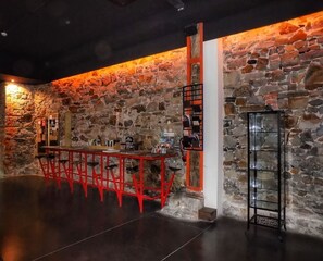 Relax with a drink at the bar, surrounded by a rustic stone wall and sleek metal accents.