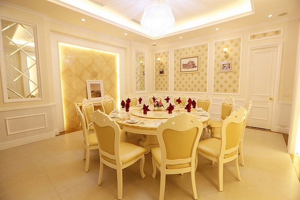 A formal dining room with a round table, six chairs, and a chandelier.
