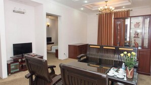 A living room with a television, a dining table with chairs, a chandelier, and a cabinet with decorative items. - Vietnam Trade Union in Hanoi (Hanoi)