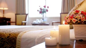 A hotel room with a bed, two lit candles, a vase with flowers, and a window with curtains. - Vietnam Trade Union in Hanoi (Hanoi)