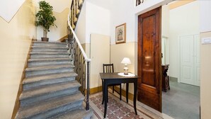 A staircase with a wooden handrail, a potted plant, a table with a lamp, and a wooden door. - L'ARANCETO&STILNOVO GUEST HOUSE DI TOKA ALFONS (Florence)