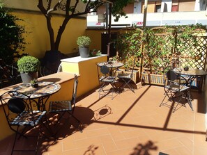 An outdoor patio area with multiple round tables and chairs, surrounded by yellow walls and potted plants. - L'ARANCETO&STILNOVO GUEST HOUSE DI TOKA ALFONS (Florence)