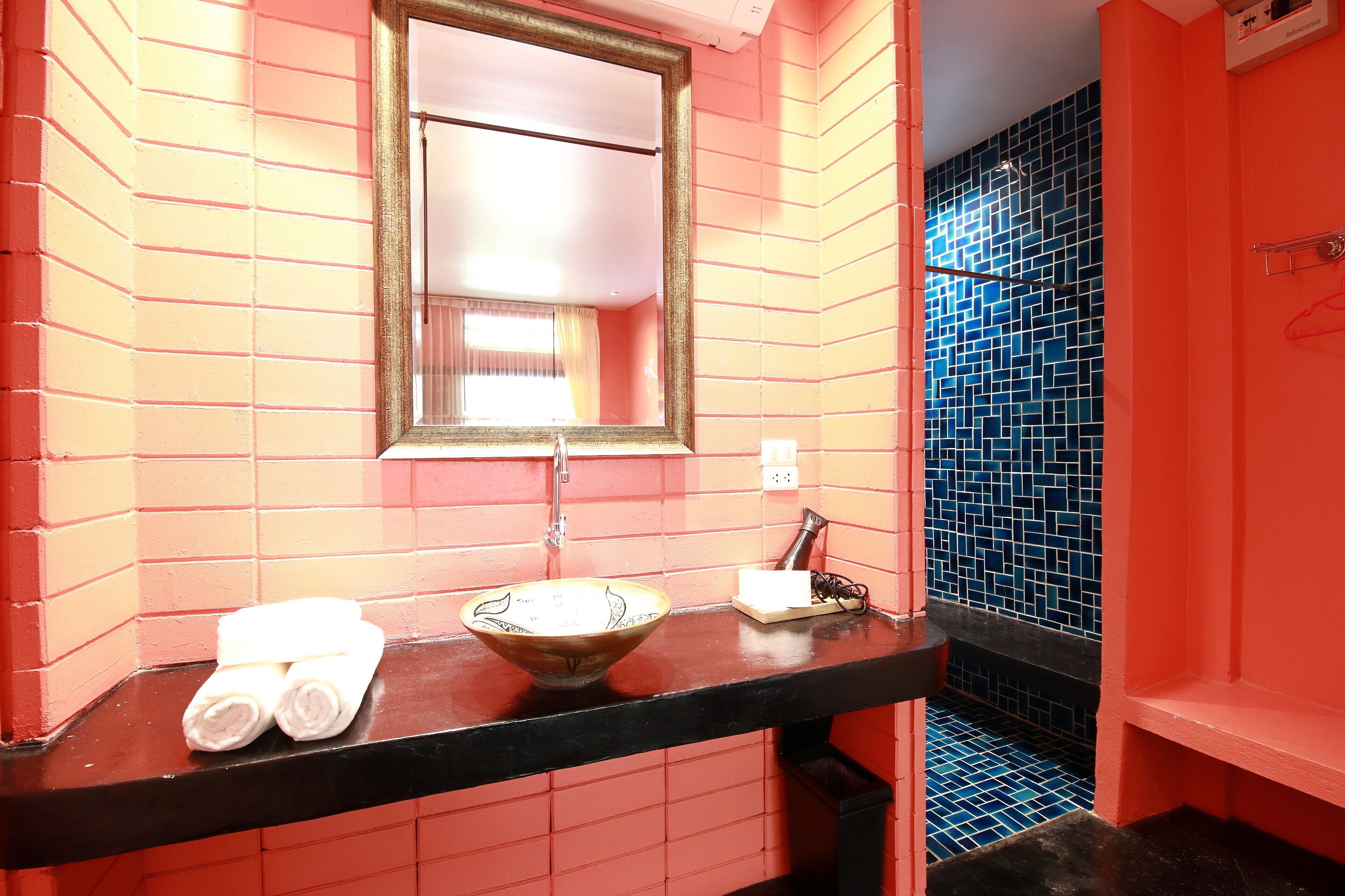 A bathroom with a black countertop, a bowl sink, and a mirror.