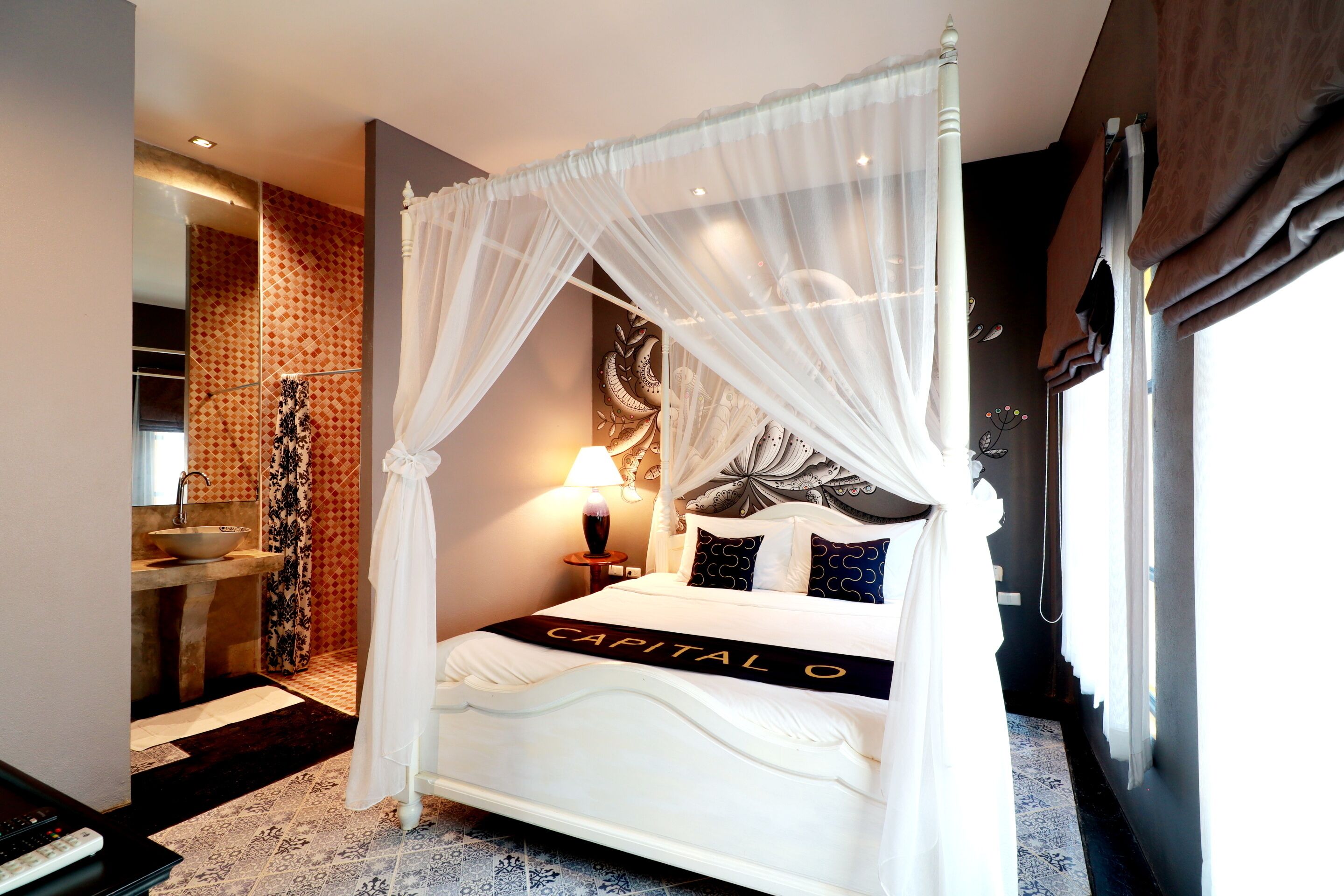 Una cama con dosel y cuatro columnas, con una colcha blanca y un cabecero decorativo.