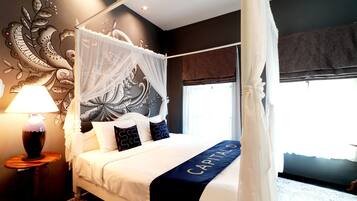 A four-poster bed with a canopy, a bedside table with a lamp, and a decorative wall mural.