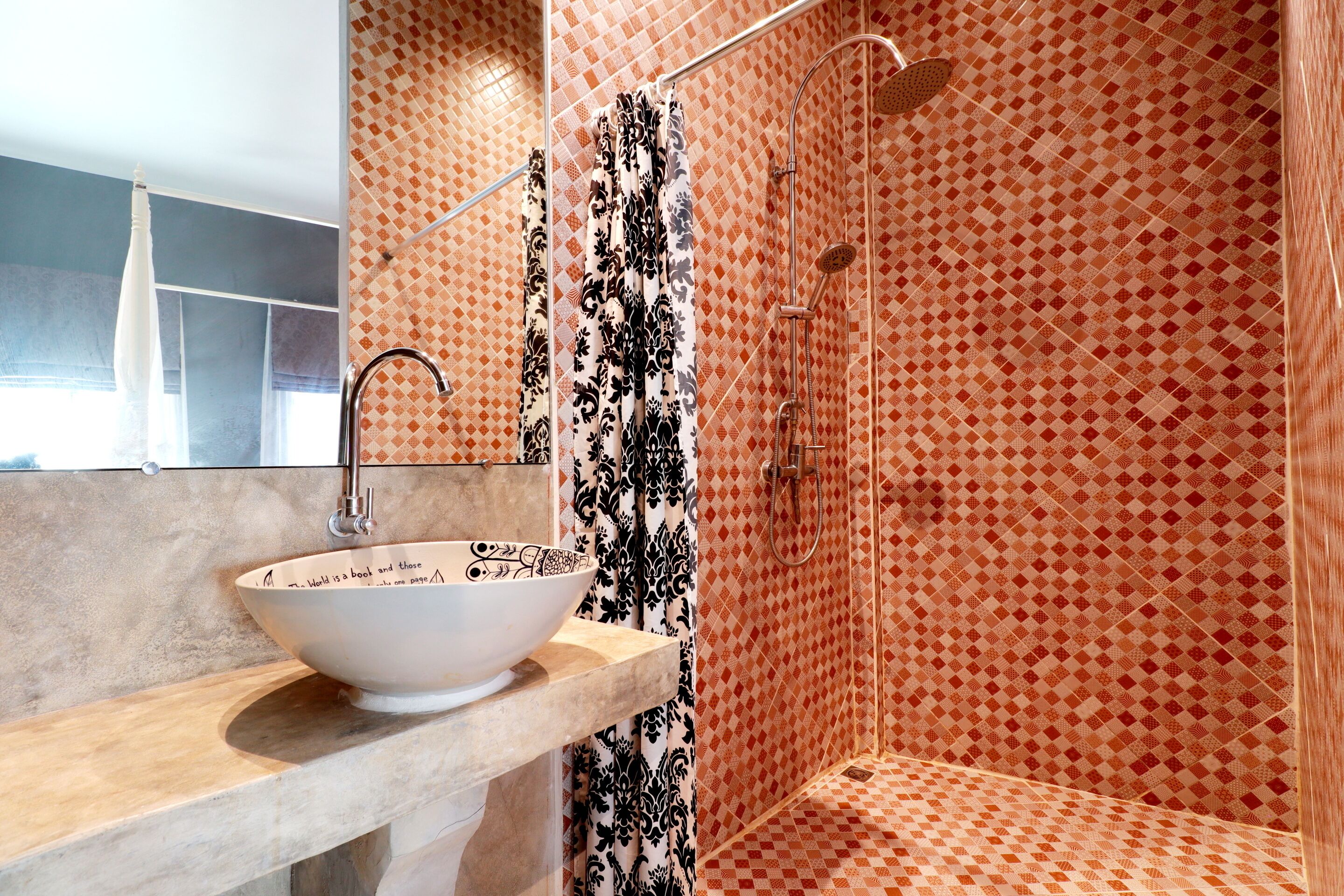 Ein Badezimmer mit einem weißen Waschbecken, einer Dusche mit einem gemusterten Duschvorhang und einer gefliesten Wand mit einem Rautenmuster.