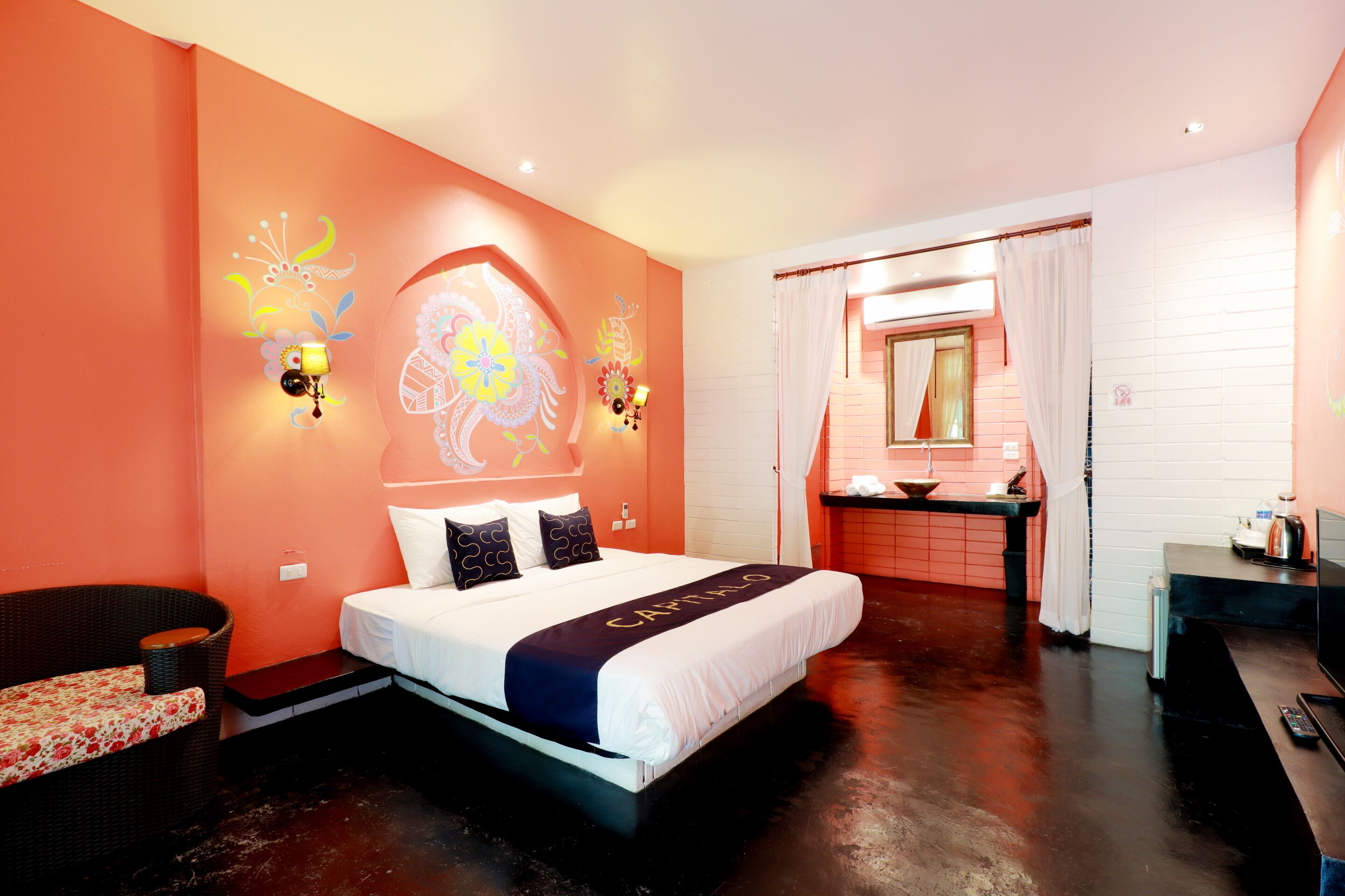 Quarto de hotel com cama, sofá, banheiro e cozinha compacta.