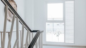 Un interior luminoso y blanco con una escalera que conduce a un balcón.