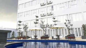Un hotel moderno con zona de piscina, mobiliario exterior y unidades de aire acondicionado.