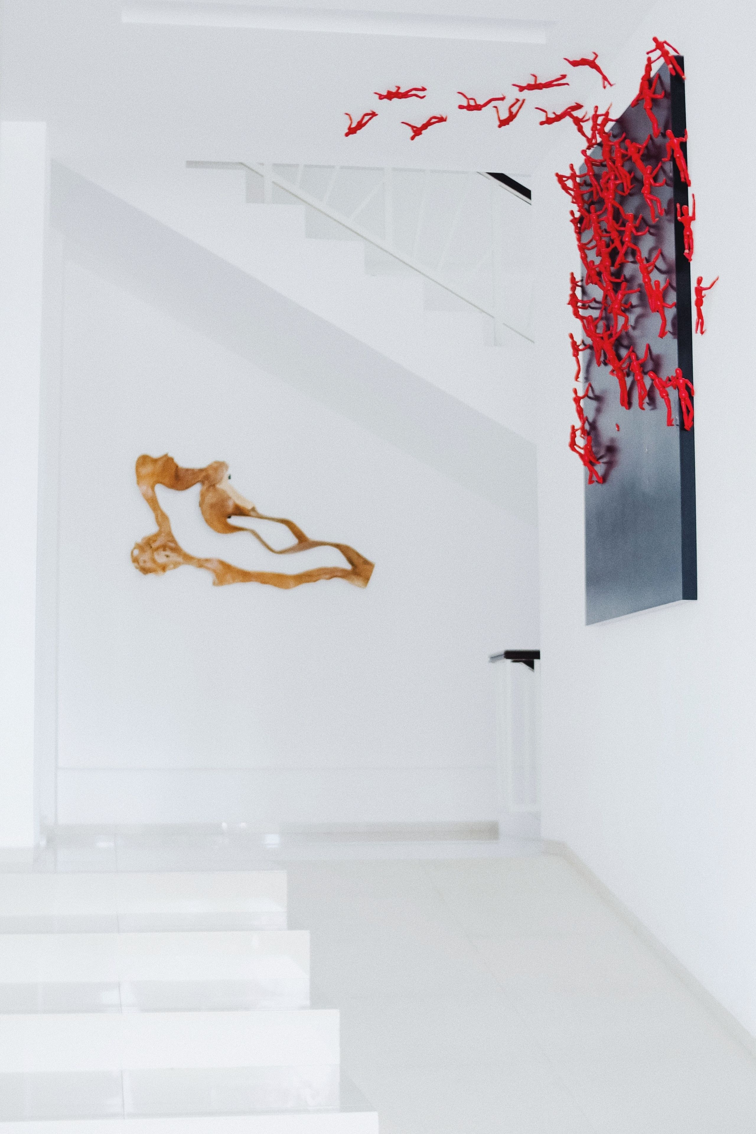A modern interior with a staircase, a minimalist wall art piece, and a unique red installation.