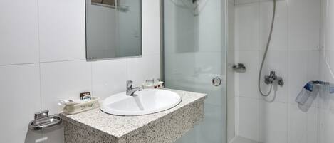 A modern bathroom with a glass-enclosed shower, a sink with a granite countertop, and a mirror above the sink.