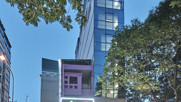 Un edificio de varios pisos con diversos comercios en la planta baja, incluyendo un salón de masajes y un restaurante.