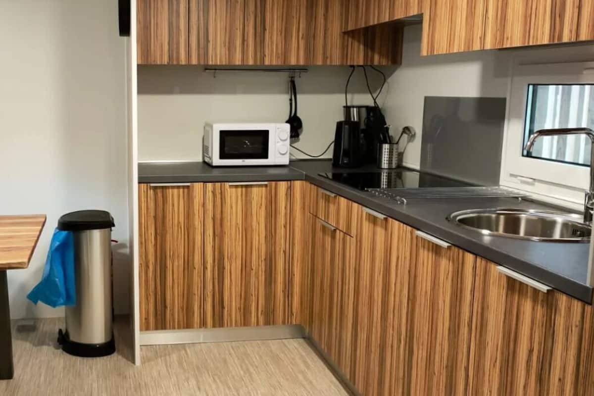 A compact kitchenette with a microwave, coffee maker, and stainless steel sink.