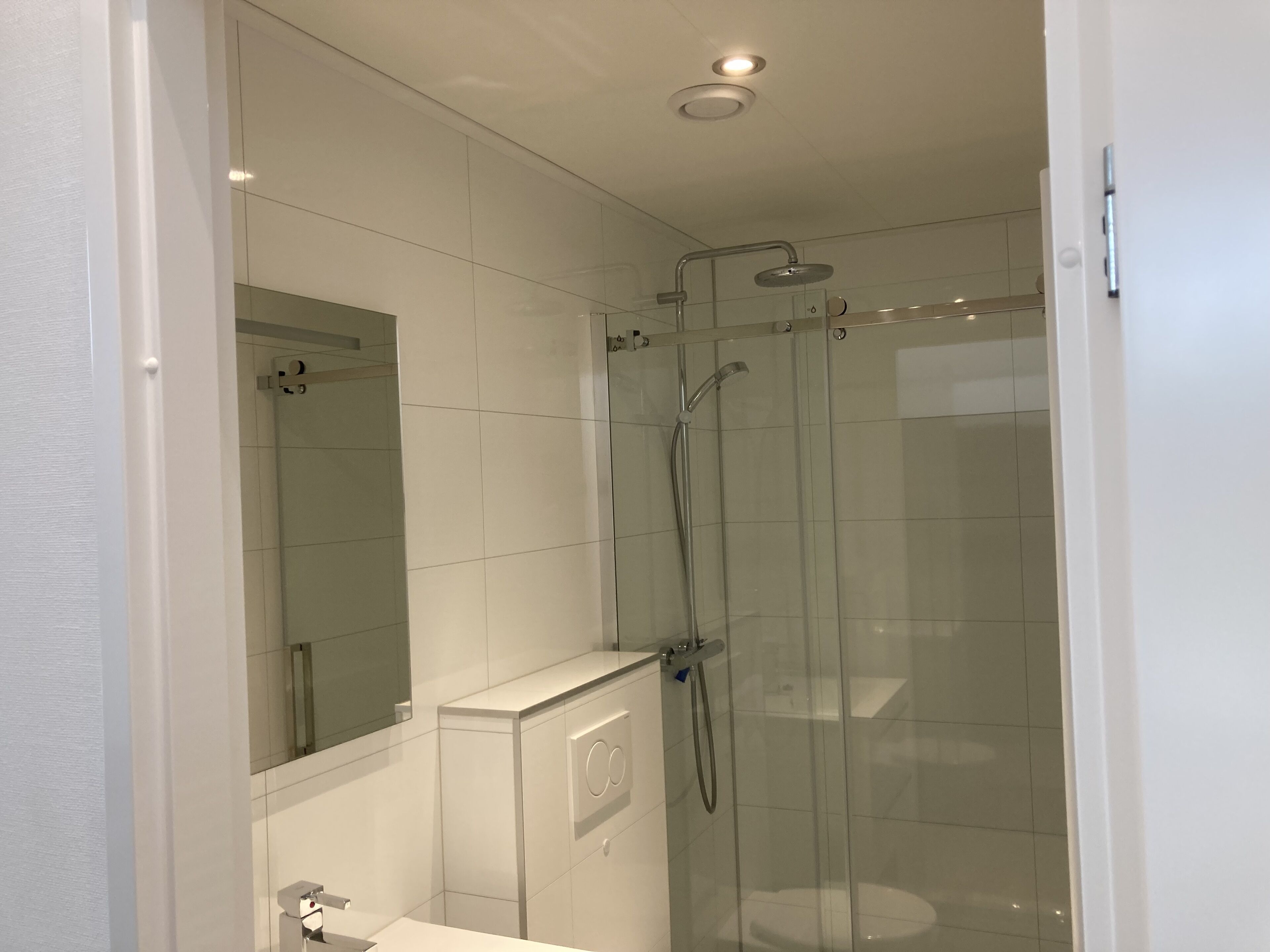 Un baño moderno con ducha de vidrio, inodoro y lavamanos.
