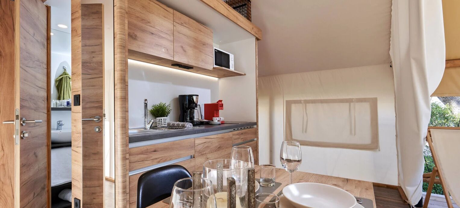 A compact kitchen with wooden cabinetry, a coffee maker, and a small sink.