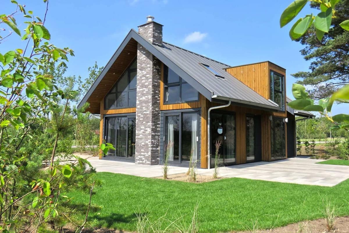 A modern house with a sloped roof, large windows, and a well-maintained lawn.