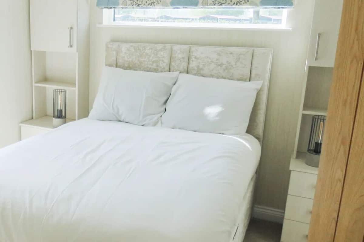 A bedroom with a bed, a nightstand, a window, and a wardrobe.