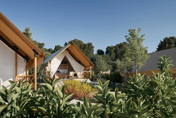 Un área de estar exterior moderna con un pérgola de madera y un dosel blanco.