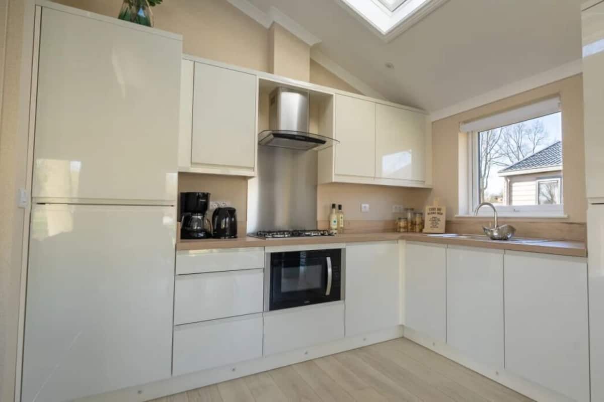A kitchen with white cabinets, a stove, a microwave, and a window.