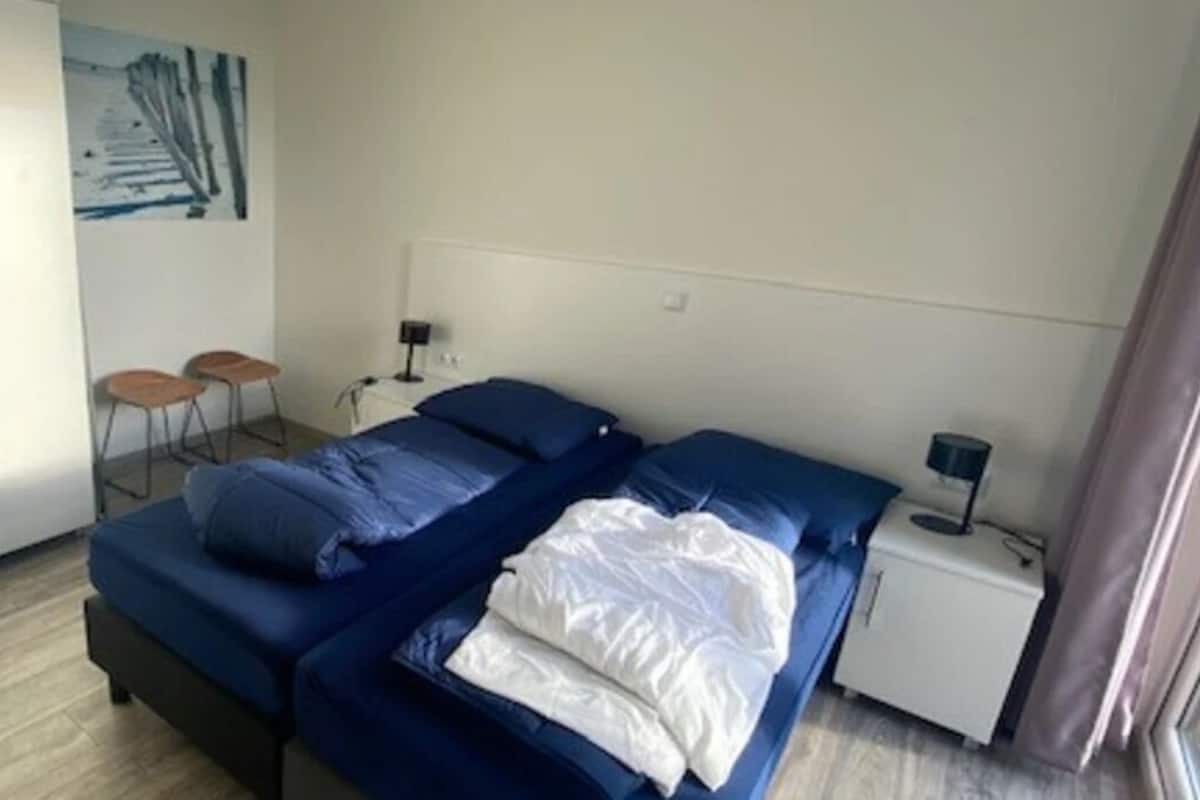 A bedroom with a bed, a nightstand, a lamp, and a painting on the wall.