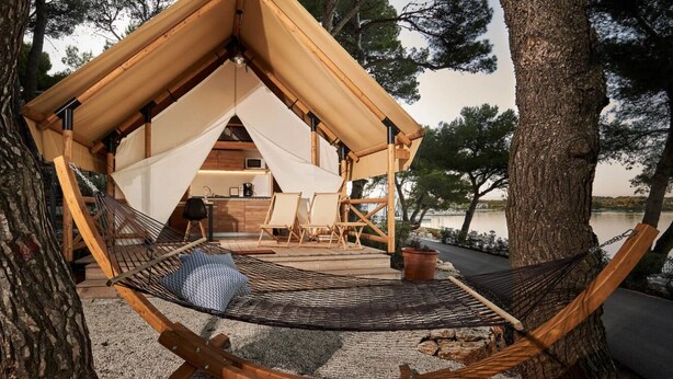 Una tienda de campaña acogedora al aire libre con una hamaca, una terraza de madera y una pequeña kitchenette.