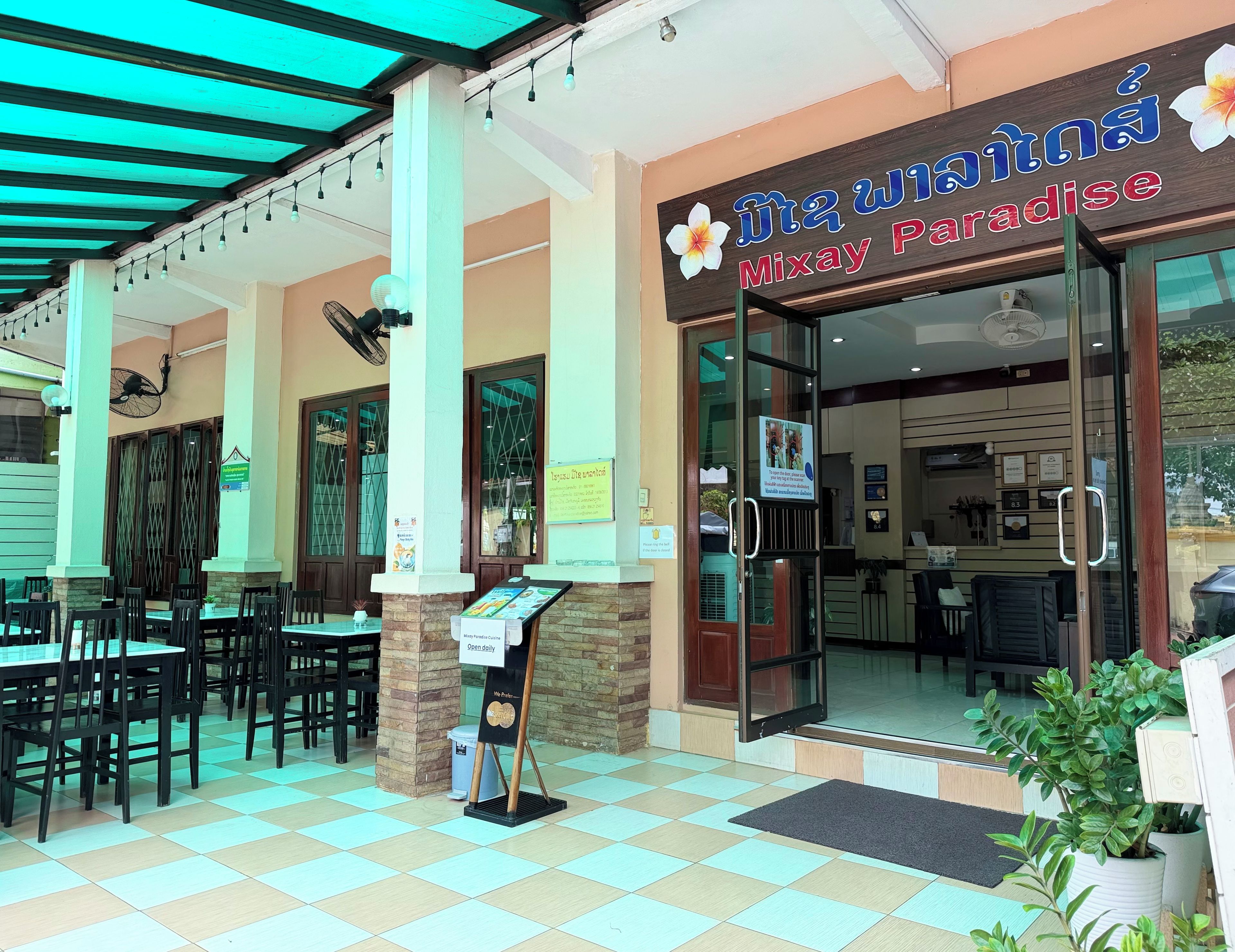 A restaurant with a sign reading 'Mixay Paradise' and a menu board outside.