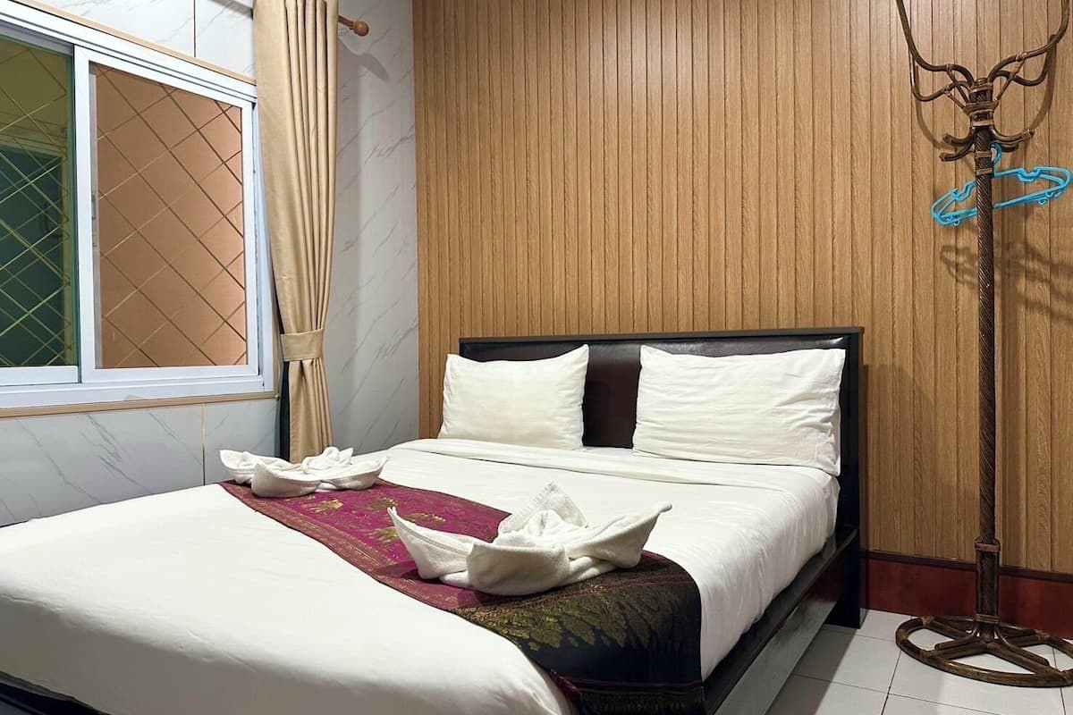 A neatly made bed with white linens, a wooden headboard, and a decorative throw.