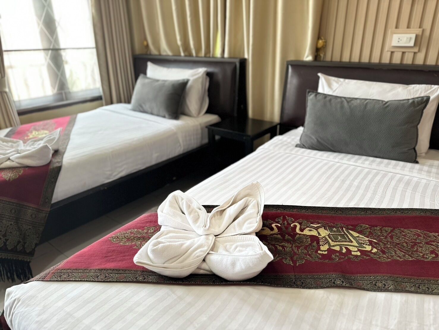 A hotel room with two beds, each with a different pillow design.