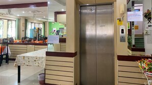 A hotel lobby with a reception desk, a dining area with tables and chairs, and an elevator. - Mixay Paradise Hotel (Vientiane)