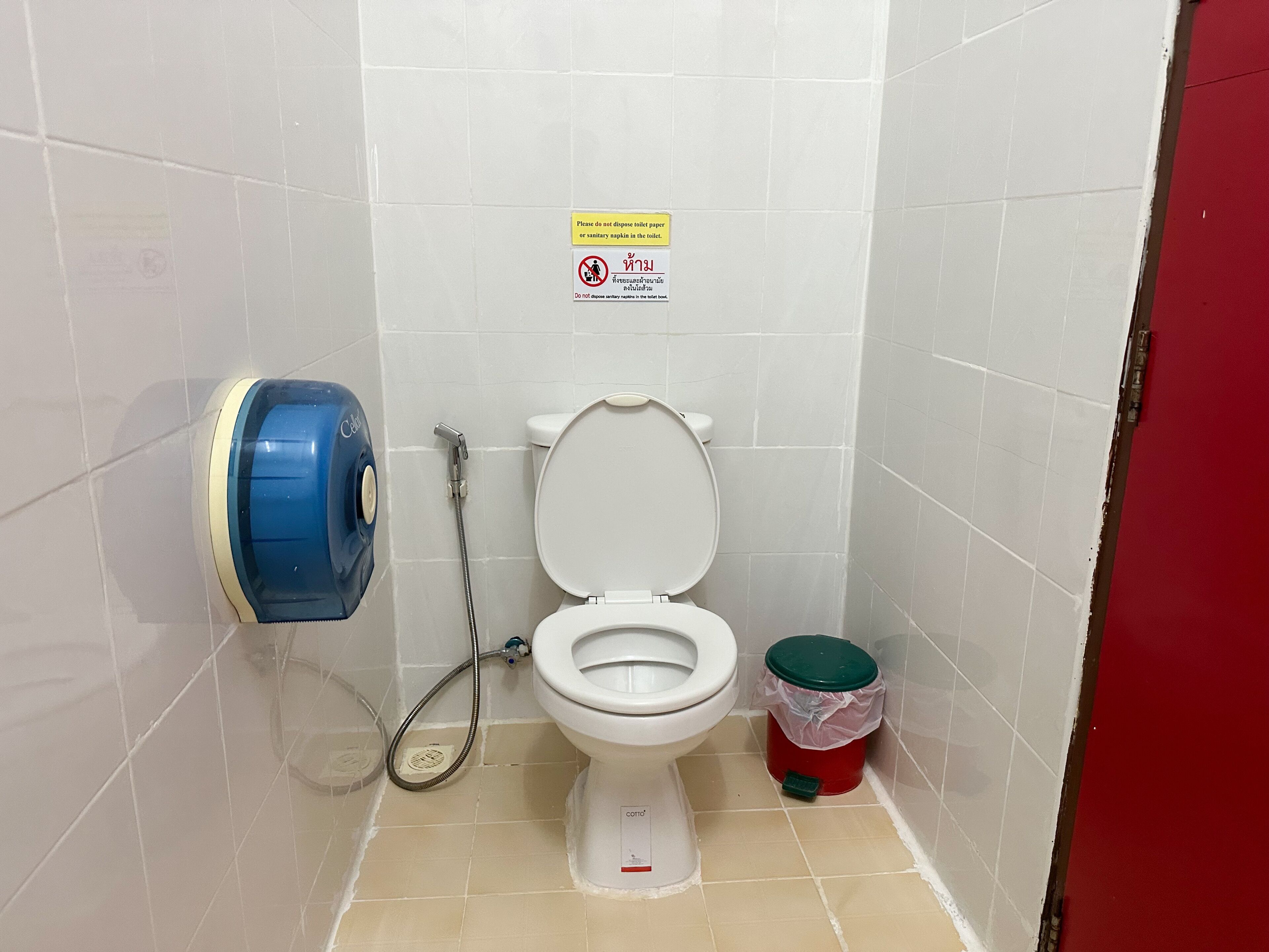 A small bathroom with a toilet, a hand dryer, and a trash bin.