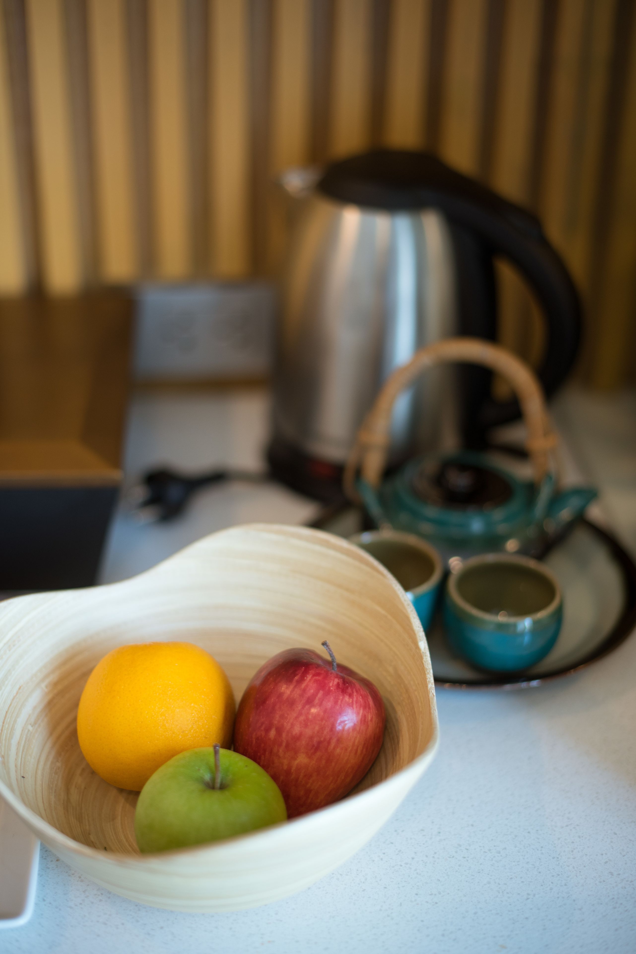 A bowl with an orange, a green apple, and a red apple on a table.