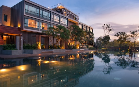 A modern hotel with a reflective pool, large windows, and outdoor lighting.