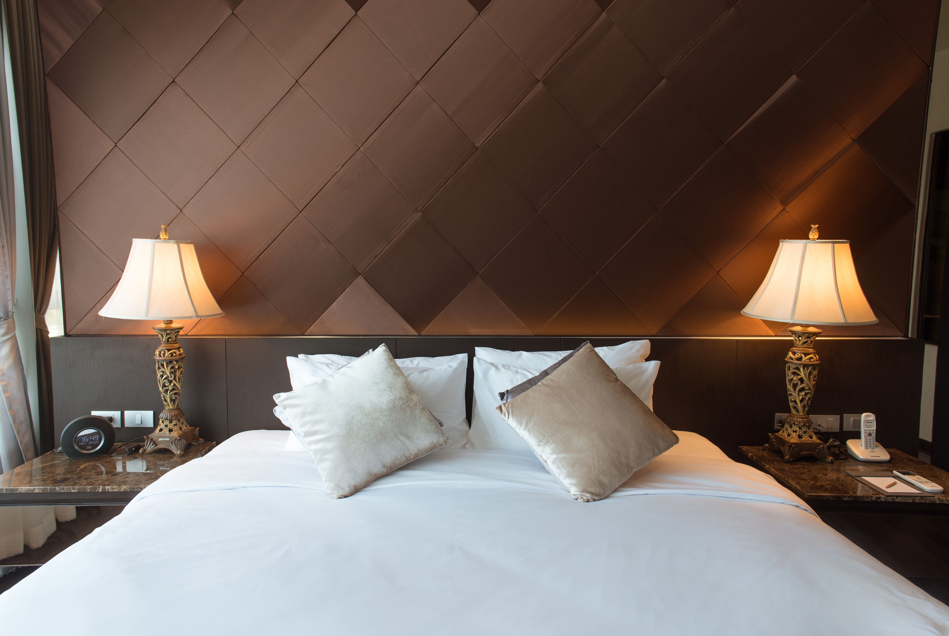Ein Hotelzimmer mit einem großen Bett, zwei Nachttischen, zwei Lampen und einem Kopfteil mit geometrischem Muster.