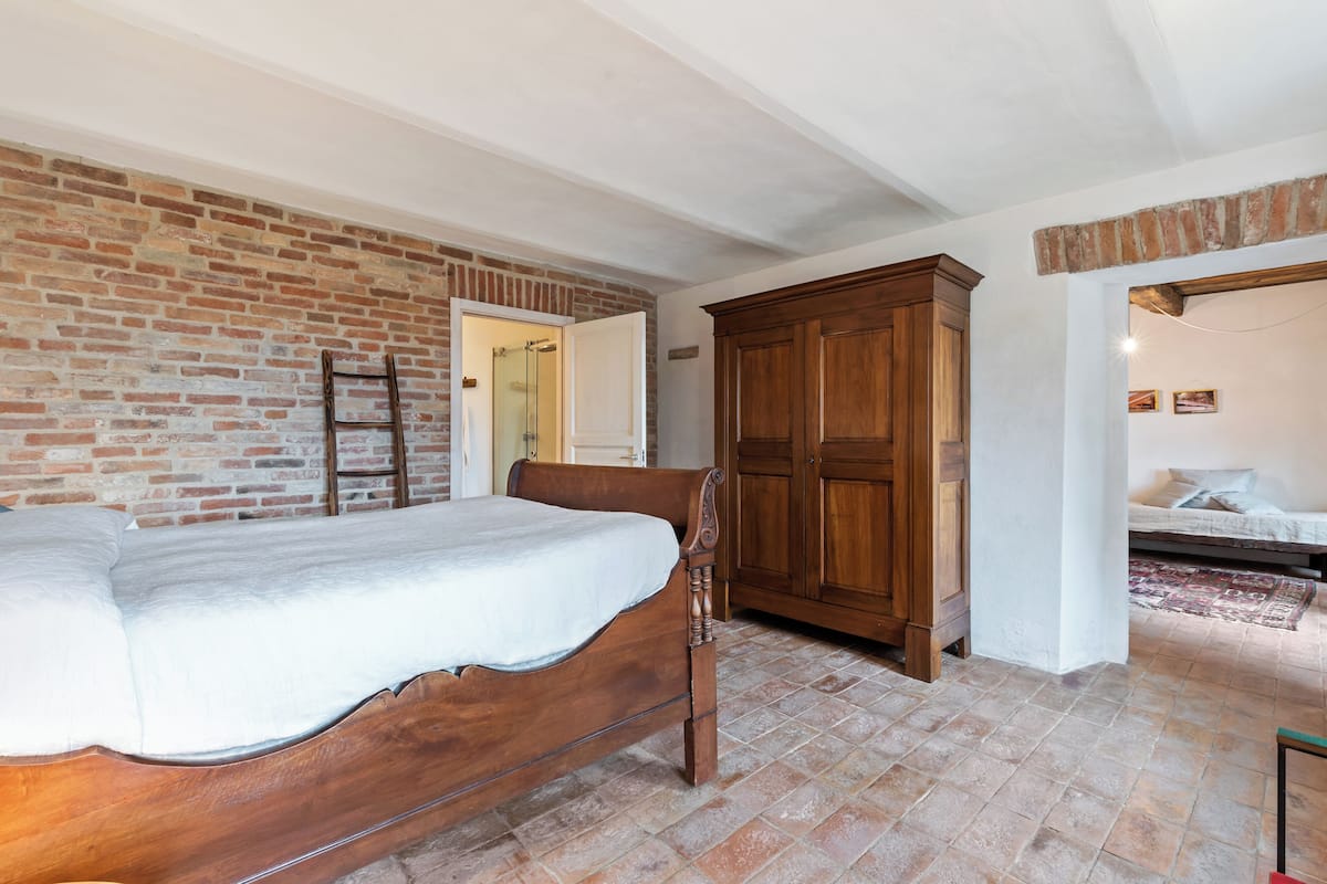 A bedroom with a wooden bed, brick wall, and a wardrobe.