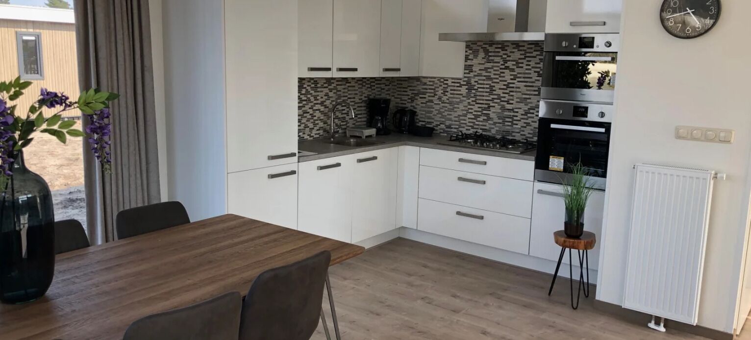 Een moderne keuken met witte kasten, een betegelde spatwand en roestvrijstalen apparatuur.