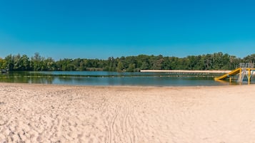 Enjoy a serene lakeside retreat with a sandy beach and a lifeguard stand for added safety.