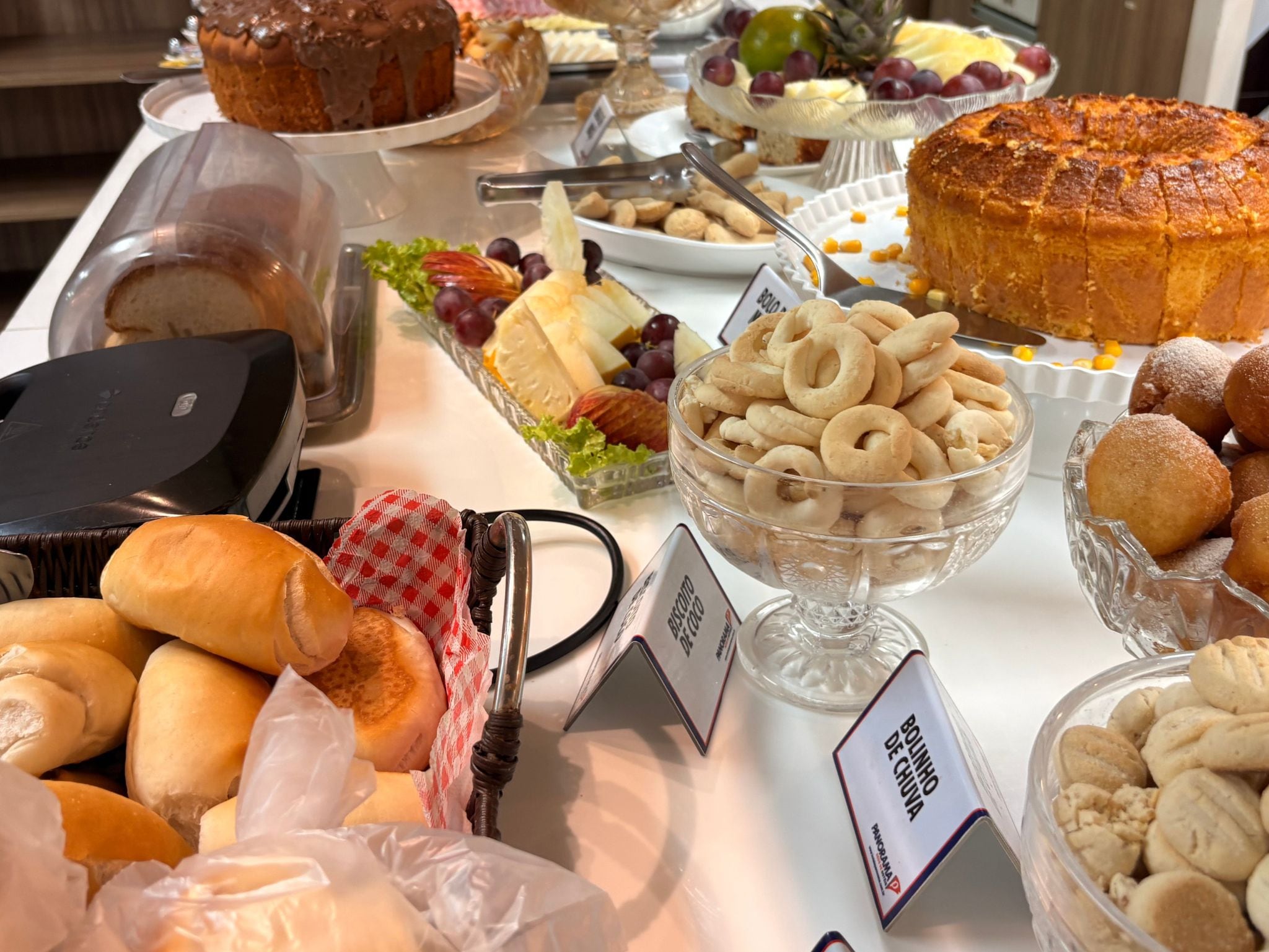 A buffet table with various food items including bread, pastries, and a cake.