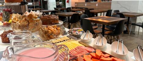A buffet with various food items including fruits, cheeses, and meats.