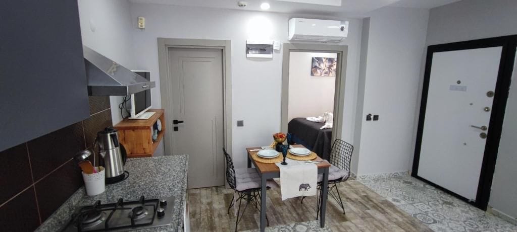 A compact kitchen with a gas stove, a coffee maker, and a dining table set for two.