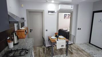 A compact kitchen with a gas stove, a coffee maker, and a dining table set for two.