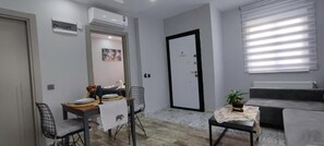 A compact living space with a dining area, a sofa, and a door. - Aspendos Suites (Konyaalti)