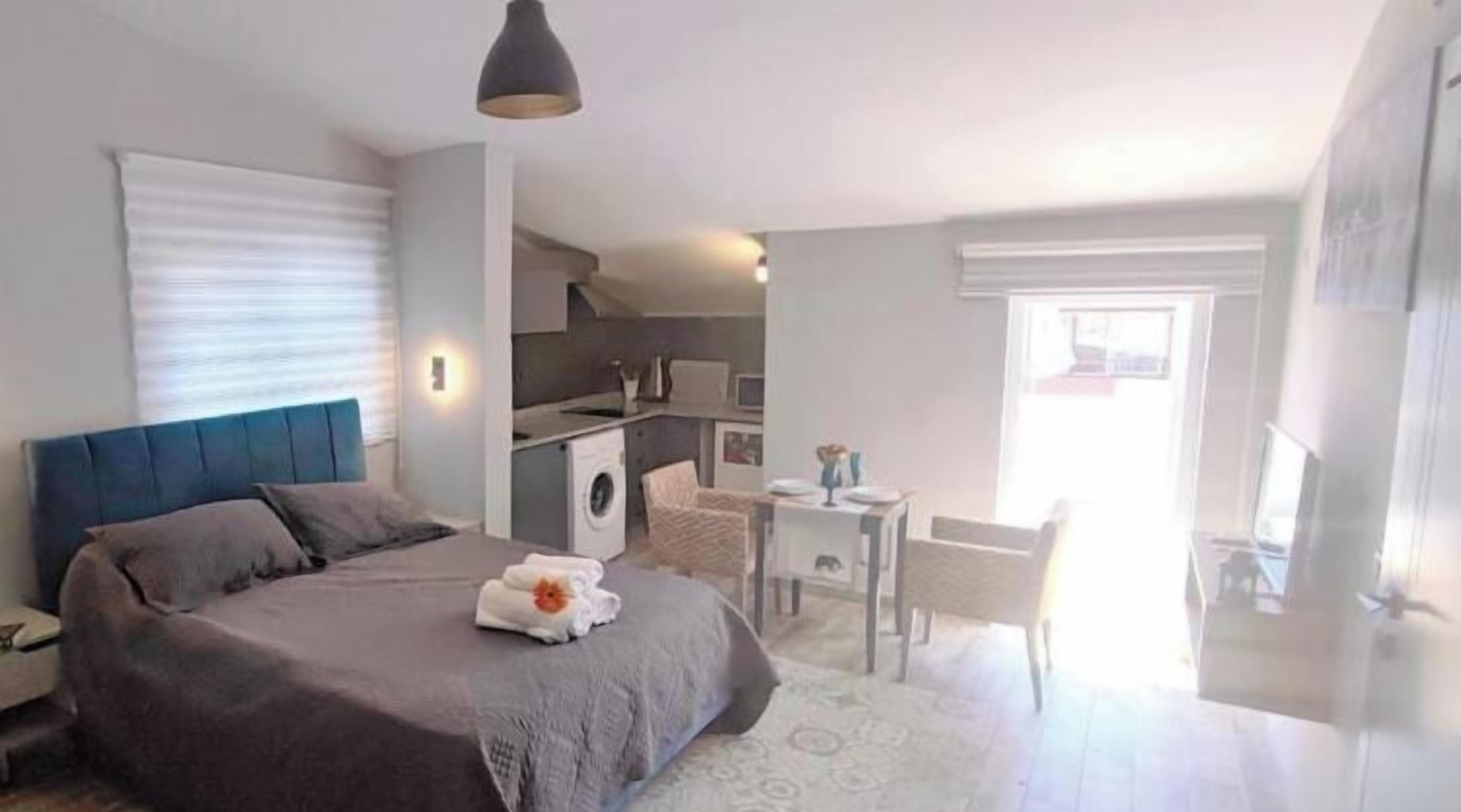 A bedroom with a bed, a desk, and a washing machine.
