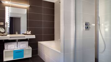 Une salle de bain moderne avec une baignoire blanche, une douche à parois de verre et un meuble-lavabo doté d’un miroir et d’un porte-serviettes.