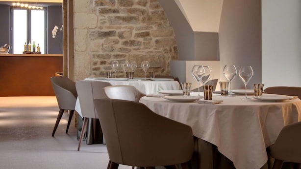 A restaurant with stone walls, white tablecloths, and modern chairs. - Hotel Mas de Boudan (Nîmes)