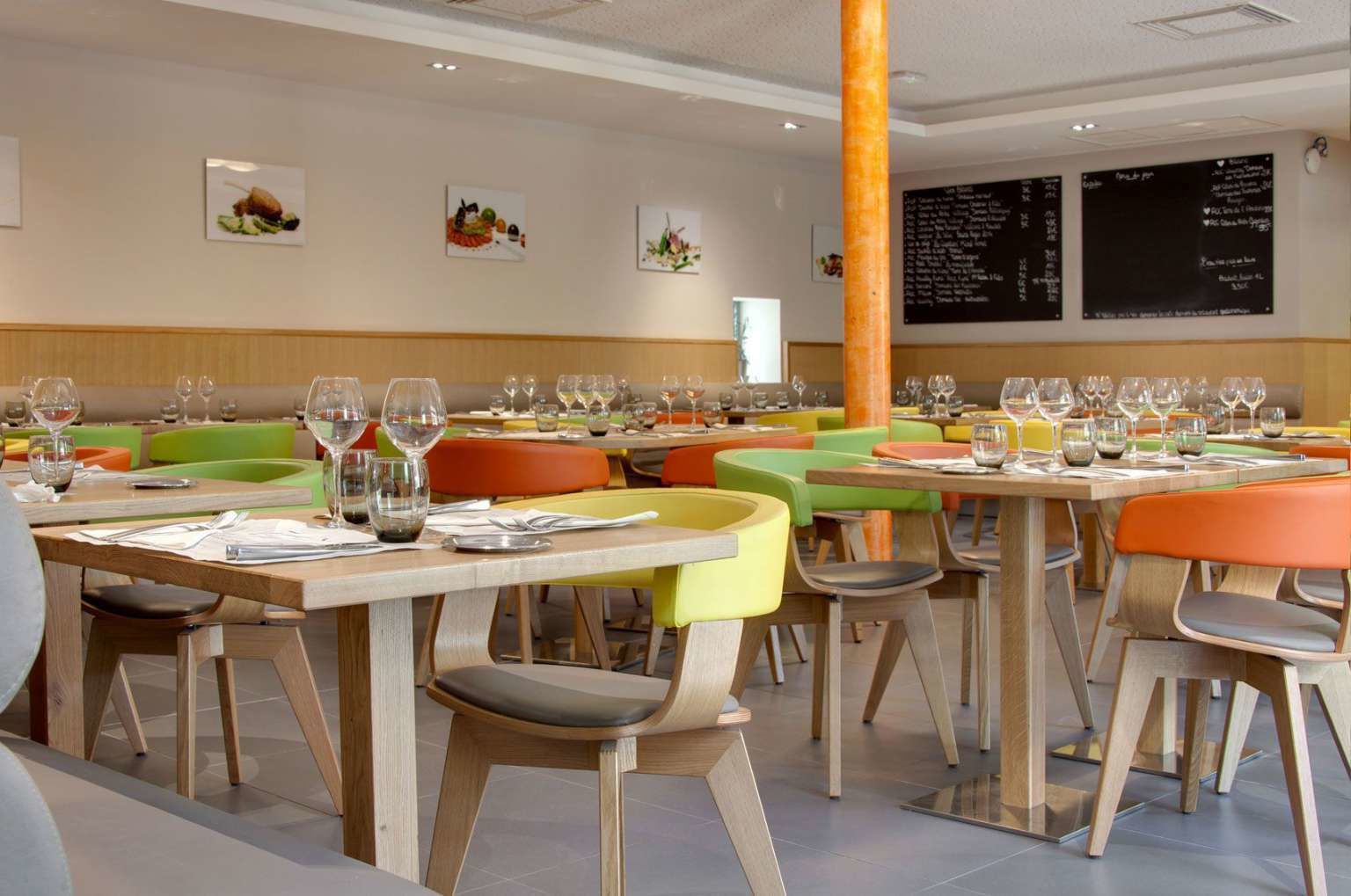 Un restaurante con varias mesas, cada una dispuesta con copas de vino, cubiertos y platos.