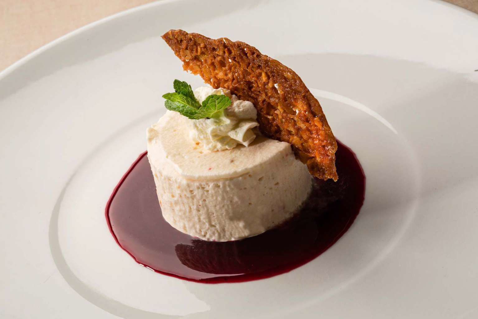 A dessert on a white plate with a red sauce.