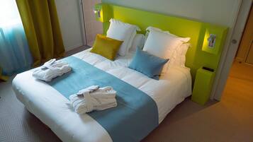 A hotel room with a neatly made bed, two pillows, a blue and white bedspread, and two towels on the bed.