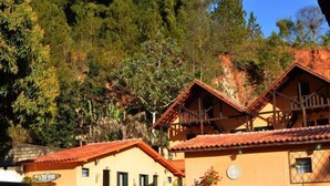 Un edificio tradicional con techo de tejas y un balcón, rodeado de abundante vegetación y árboles.