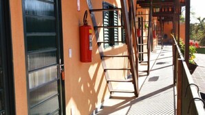 Un espacio al aire libre techado con una escalera metálica, un extintor y una puerta con un letrero de número.