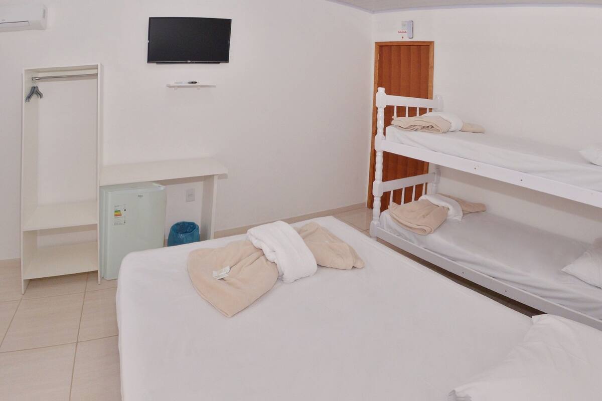 Une chambre d’hôtel équipée d’un lit, d’un téléviseur fixé au mur, d’une armoire et d’un petit bureau avec une poubelle.